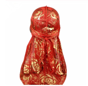 Detail view of red silky durag featuring golden rose patterns and long tail draping