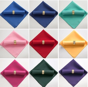 Nueve servilletas de colores azul, rojo y verde con servilleteros de metal dorado tallado