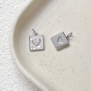 Macro detail of gold-plated heart charms with mother of pearl inlays on a tray