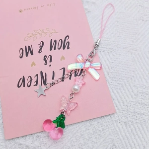 Pink bow and cherry phone charm with star pendant on elegant white lace background