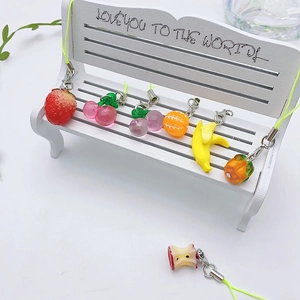 Creative fruit phone charms set with resin strawberry and banana on a white bench