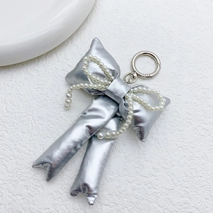 Close-up of shiny silver bow keychain with elegant pearl chain and metal ring detail