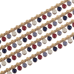 Close-up of golden enamel bead chain with red, blue and grey charms for DIY jewelry making