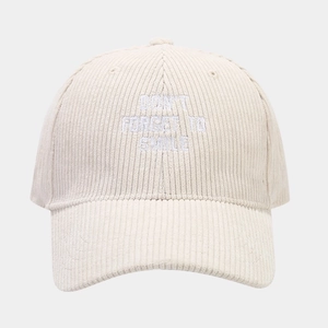 Detail of embroidered 'DON'T FORGET TO SMILE' text on cream corduroy baseball cap