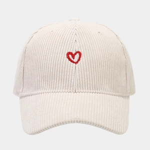 Close-up of a beige corduroy baseball cap featuring detailed red heart embroidery