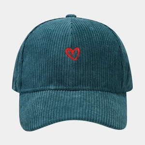 Detail of dark green corduroy baseball cap with red heart embroidery texture