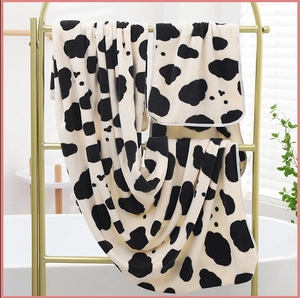 Close-up of soft cow print coral fleece towel set hanging on a gold metal rack