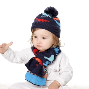 Close-up of knit baby hat and scarf set with orange dinosaur pattern and soft lining