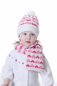 Close-up of white and pink knit infant hat and scarf set with heart patterns