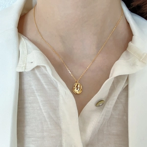 Close-up of a minimalist 925 silver necklace with a gold organic shape pendant on a model