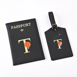 Detail of black passport holder and luggage tag set with golden letter T and balloon