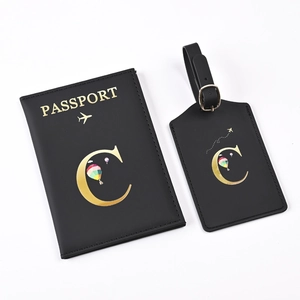 Detail of black PU leather passport holder and luggage tag set with golden letter C design