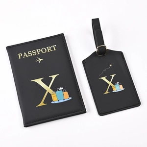 Close-up of black PU leather passport holder and luggage tag set with golden letter X