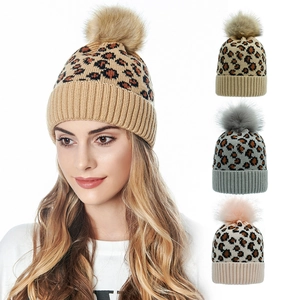 Detail of leopard print knit beanie featuring a fluffy faux fur pom and ribbed cuff design