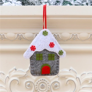 Close-up of grey and white felt house ornament hanging from a snowy pine branch