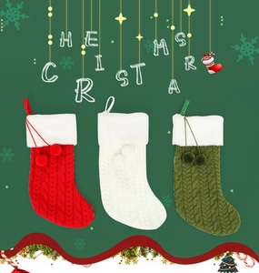 Detail of cable knit Christmas stockings with plush white trim and decorative pom-poms
