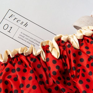 Detail view of waterproof red polka dot shower cap with elegant beige ruffled satin edge