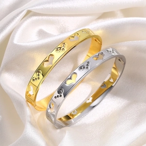Titanium steel hollow heart bangles with crystals in gold and silver on white silk