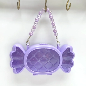 Dettaglio della borsa porta gioielli viola a forma di caramella con manico di perle