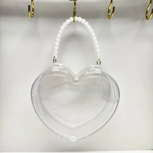 Dettaglio di una borsa trasparente a forma di cuore con elegante manico in perle bianche