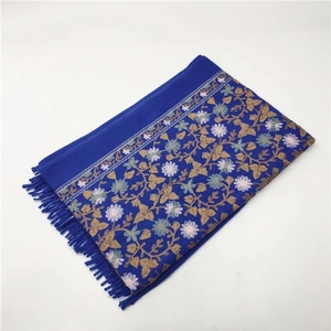 Detailed view of dark blue scarf with floral embroidery and decorative fringe edges