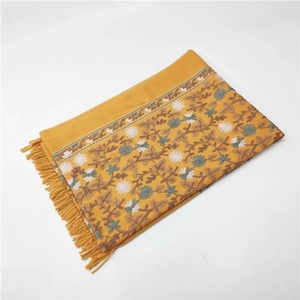 Close-up of yellow pashmina shawl with intricate floral embroidery and knotted fringes