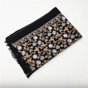 Close-up of black cashmere-like shawl featuring intricate floral embroidery and fringe