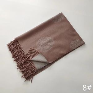 Detail of soft winter scarf with brown tree patterns and tassel edges on white background