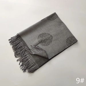 Detailed view of gray faux cashmere scarf featuring tree patterns and soft fringe tassels