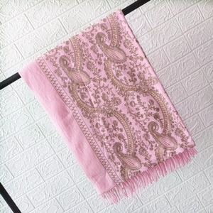 Close-up of pink cashmere shawl featuring golden paisley embroidery and elegant fringe details