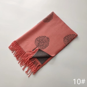 Detailed view of pink and brown cashmere-like scarf featuring tree patterns and fringed edges