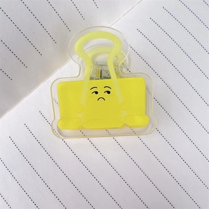 Dettaglio della molletta in acrilico giallo con faccina buffa su carta a righe