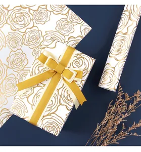 Detail of luxury white gift wrapping paper with elegant gold rose line art and golden ribbon