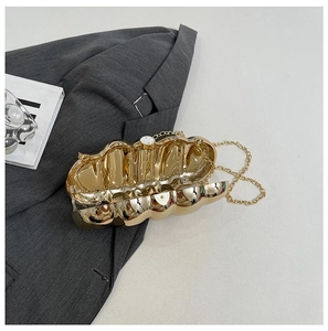 Detail of the golden wave-shaped hard shell evening clutch with a metallic chain strap