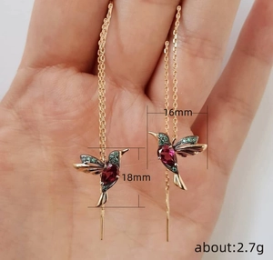 Detail shot of dainty hummingbird drop earrings with red and green cubic zirconia stones