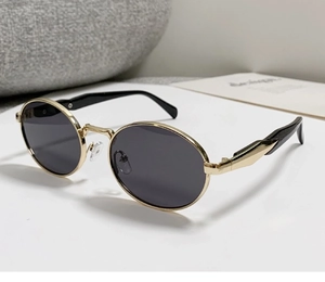 Detail einer ovalen Vintage-Sonnenbrille mit Goldrahmen und schwarzen Gläsern im Profil