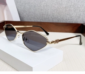 Detail of gold metal hinge with M logo on stylish vintage rhombic sunglasses