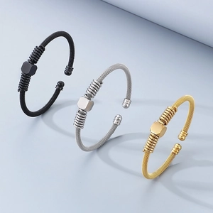 Three twisted cable steel cuff bracelets in gold, silver, and black with hexagonal motifs