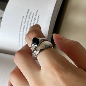 Close-up of 925 sterling silver ring set with black agate on hands over a book