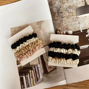 Close-up of silk satin scrunchies in neutral earth tones on branded display cards