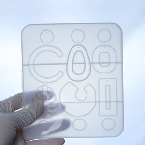 Detail showing translucent silicone mold with geometric shapes and letters for DIY resin crafts