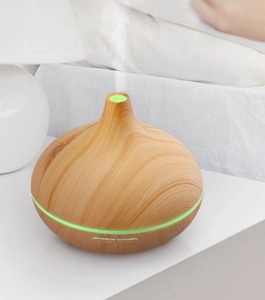 Close-up of wood grain ultrasonic diffuser featuring green LED light and mist outlet