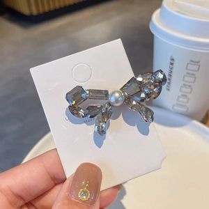 Detailed close-up of a bow hair clip with smoky crystals and a central white pearl