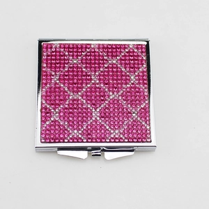 Pink rhinestone portable folding makeup mirror with sparkling mosaic pattern on white background