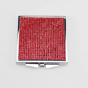Square silver folding makeup mirror with red rhinestones on a white background