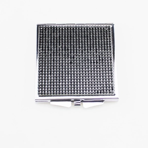 Detailed close-up of a square folding makeup mirror with a black textured dotted cover