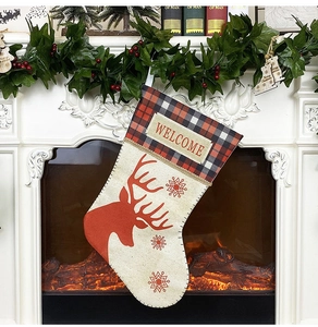 Détail d'une chaussette de Noël en toile avec motif renne et broderie Welcome sur manteau
