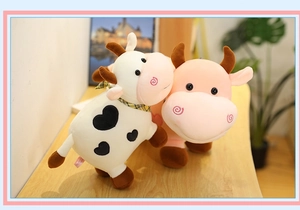 Primer plano de lindos peluches de vaca en rosa y blanco-negro sobre mesa de madera