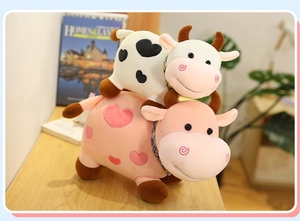 Primer plano de peluches de vaca rosa y blanco con corazones en tela suave