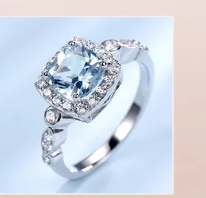Macro shot of silver ring featuring square blue gemstone with halo diamond setting
